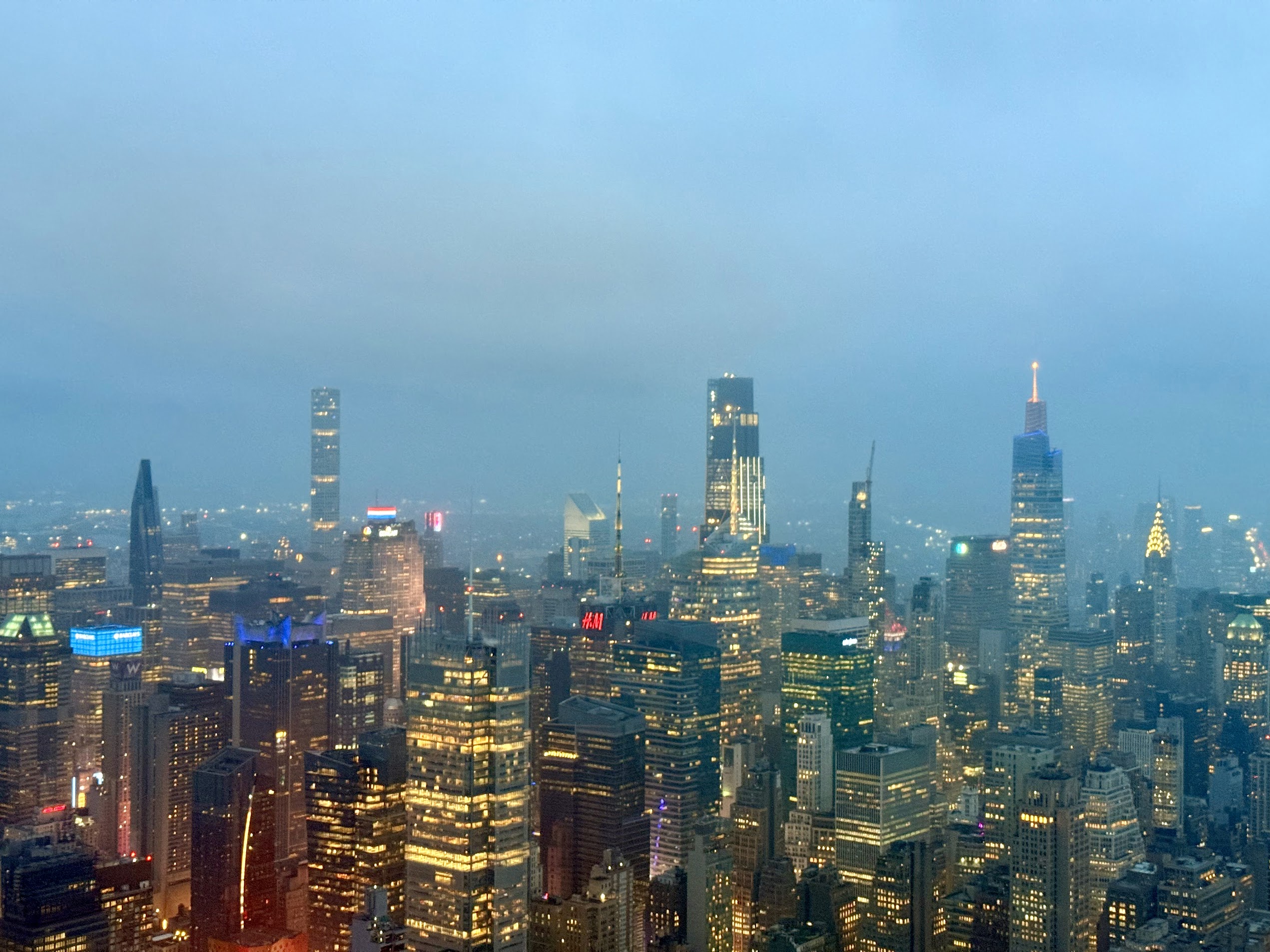 Illuminated Manhattan skyscrapers beneath a blue evening sky
